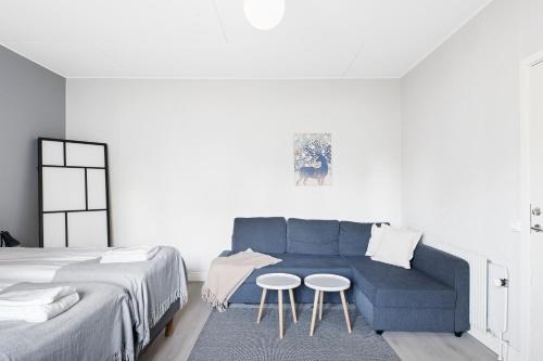 a bedroom with a blue couch and two tables at Uppsala Lägenhetshotell in Uppsala