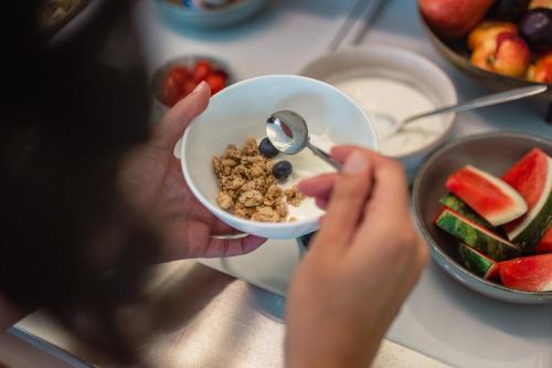 a person is holding a bowl of cereal and fruit at Frühstückspension Spitzauer in Nittendorf