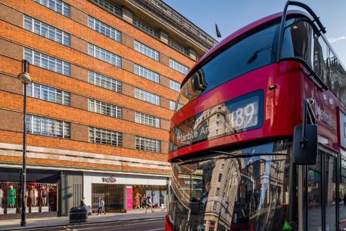 a red double decker bus parked in front of a building at The Marble Arch Hotel, by Thistle in London