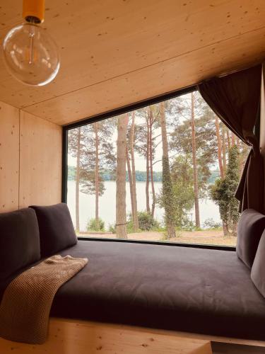 a couch in a room with a large window at Tiny Houses & Schwedenhäuser Ahoi Camp Canow in Wustrow