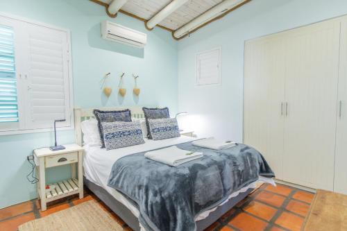 a bedroom with a bed with blue walls and a window at Malmok in Paternoster