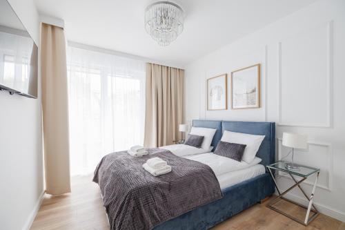 a bedroom with a bed with a blue head board at Rezydencja Merwede Aparthotel - My Rest in Gdańsk