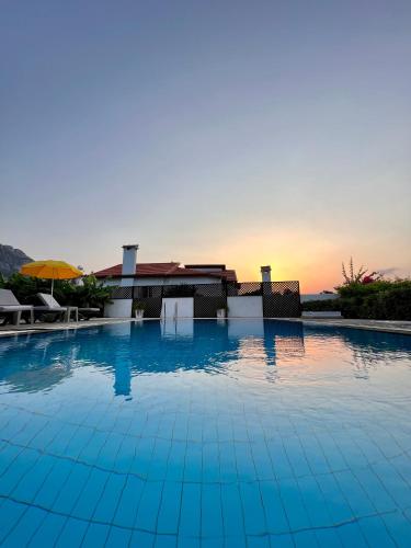 a large swimming pool with a sunset in the background at Villa Lapethos in Kérynia