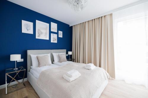 a blue bedroom with a bed with towels on it at Rezydencja Merwede Aparthotel - My Rest in Gdańsk