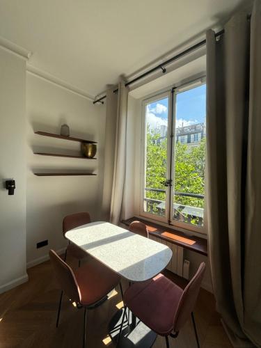 une pièce avec une table, des chaises et une fenêtre dans l'établissement Central Apartment Tronchet 1G, à Paris