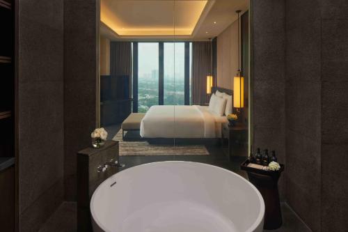 a bathroom with a bath tub and a bed at Hotel Tentrem Jakarta in Serpong