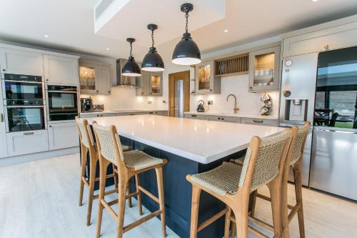 a kitchen with a large island with chairs around it at La Flora -Bracklesham Bay in Chichester