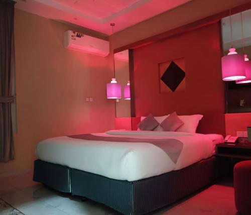 a red bedroom with a bed with pink lighting at SAHARI ALFORSAN HOTEL Sabya فندق صحاري الفرسان in Şabyā