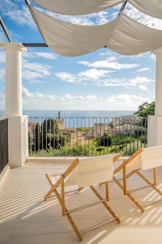 a balcony with two chairs and a view of the ocean at Villa Certosa in Capri