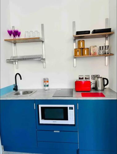a kitchen with blue cabinets and a sink at Central Southsea Studio, Perfect for work or Leisure, Central, Parking, self check-in, modern and comfortable in Portsmouth