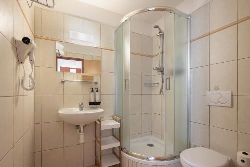 a bathroom with a shower and a sink and a toilet at Pytloun Kampa Garden Hotel Prague in Prague