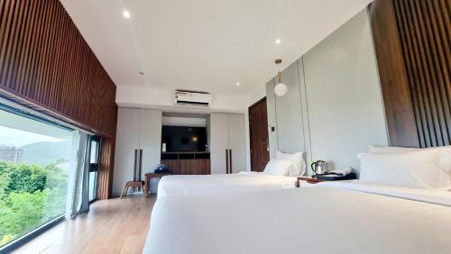 a hotel room with two beds and a large window at Anh Nguyen Oceanfront Luxury Villas Nha Trang in Nha Trang