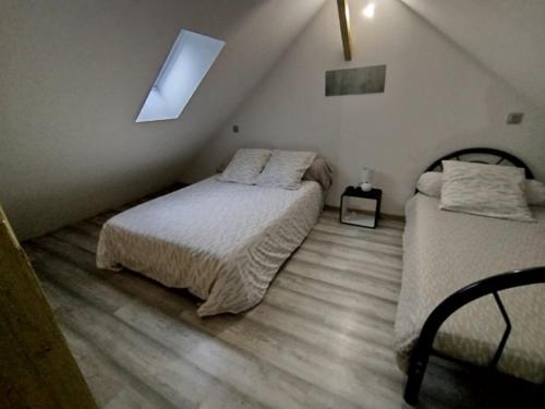 a attic bedroom with two beds and a window at maison luxe cléo aeroport tillé 4 personnes in Tillé