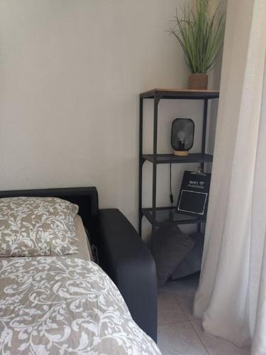 - une chambre avec un lit et une étagère avec une plante dans l'établissement Studio grande terrasse proche gare et mer, à Menton