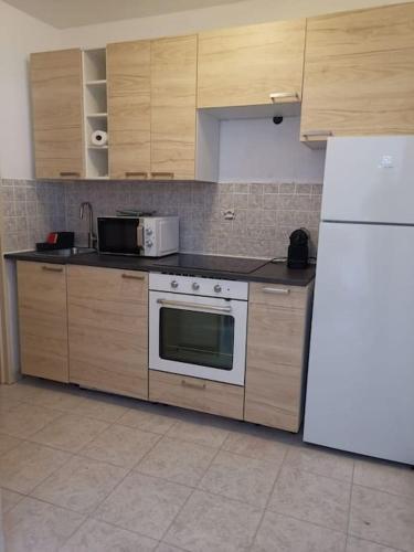 La cuisine est équipée d'une cuisinière blanche et d'un réfrigérateur. dans l'établissement Studio grande terrasse proche gare et mer, à Menton