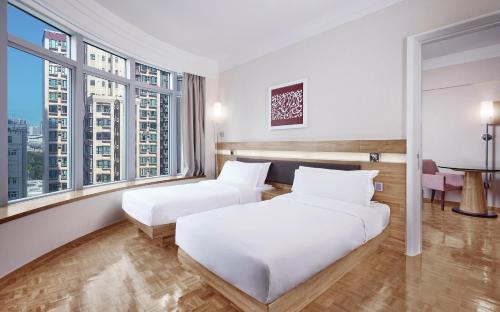 a hotel room with two beds and large windows at Nina Hotel Causeway Bay in Hong Kong