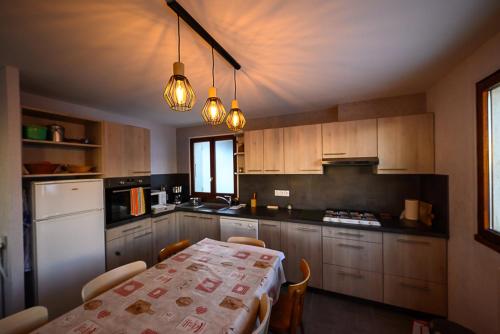 Il comprend une cuisine équipée d'une table, d'un réfrigérateur blanc, d'une table et de chaises. dans l'établissement chalet Les Aplanes appt, à Albiez-Montrond