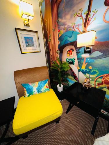 a room with a yellow chair and a painting at Merchant Hotel in George Town