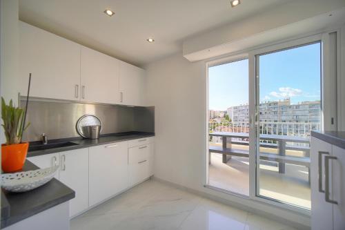 une cuisine avec des placards blancs et une grande fenêtre dans l'établissement Coco - Spacieux - Luxueux - VCA, à Cannes