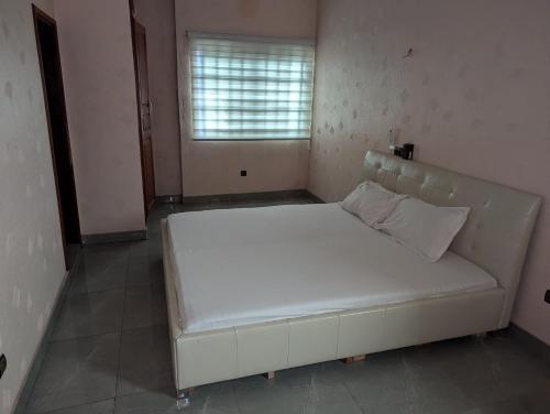 a large white bed in a room with a window at Domicile Cotonou in Cadjèhoun