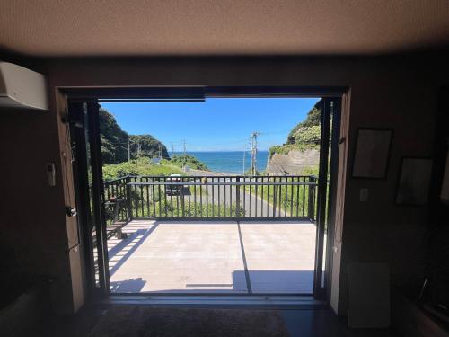 a door to a balcony with a view of the ocean at 海辺の別荘in竹岡 in Hagyū