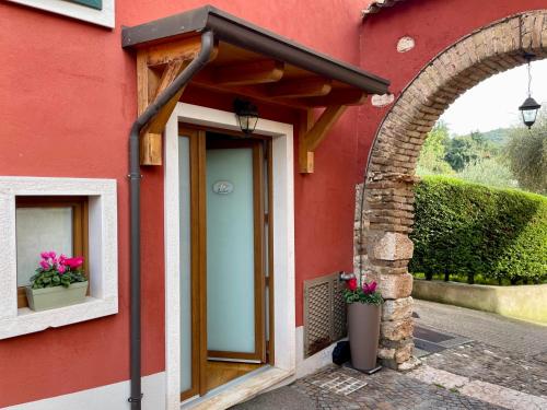 a red house with an archway and flowers on the door at Relais Fontana Rosa B&B Wellness in Caprino Veronese