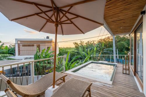 an umbrella and chairs on a deck with a swimming pool at Pagi Villas by Betterplace in Canggu