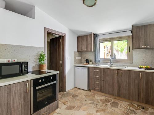 a kitchen with wooden cabinets and a microwave at Andre Marie Stonewood Retreat in Limassol