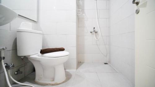 a white bathroom with a toilet and a shower at Spacious 2BR Connected to Mall at Anderson Supermall Mansion Apartment By Travelio in Surabaya