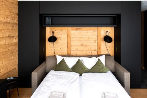 a bedroom with a white bed with green pillows at Andermatt Alpine Apartments in Andermatt