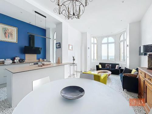 un salon avec une table blanche et un mur bleu dans l'établissement Les Lutins - sur la plage, à Wimereux