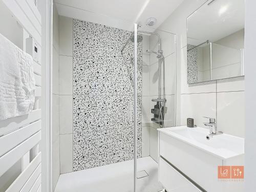une salle de bain blanche avec une douche et un lavabo dans l'établissement Les Lutins - sur la plage, à Wimereux
