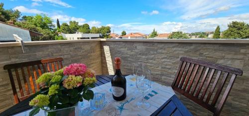 a table with a bottle of wine and flowers on it at Apartments Tena in Rovinj