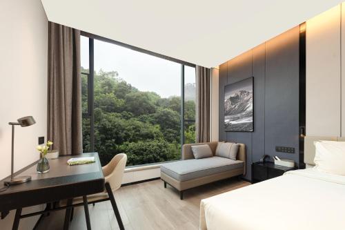 a hotel room with a bed and a desk and a window at Atour Hotel Xiamen Huli Nanshan Road in Xiamen
