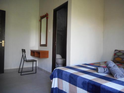 a bedroom with a bed and a chair and a mirror at Terrace Homestay Besakih in Besakih