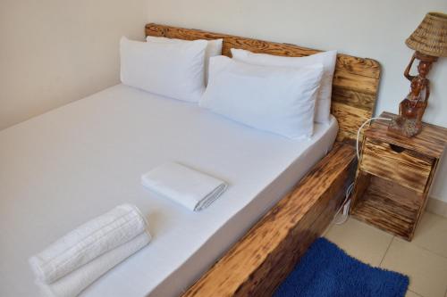 Una cama con sábanas blancas y almohadas en una habitación. en Tajari Diani Beach Condo, en Galu