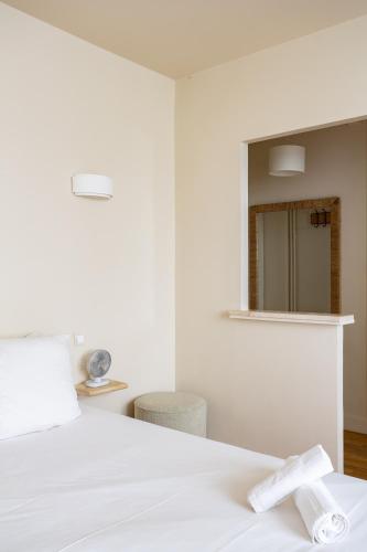 une chambre avec un lit blanc et un miroir dans l'établissement The Charming Saint Honoré, à Paris