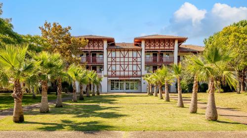 a building with palm trees in front of it at Résidence Pierre & Vacances Le Domaine de Gascogne in Biscarrosse