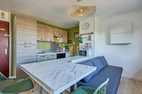 un salon avec une table et un canapé bleu dans l'établissement Les Jardins du Val Pican - Appt proche de la mer, à Courseulles-sur-Mer