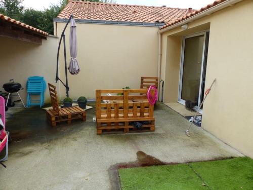 - une terrasse avec 2 chaises en bois et un parasol dans l'établissement Maison proche aéroport, à Saint-Aignan-Grand-Lieu