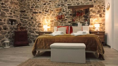 a bedroom with a bed with a stone wall at Apartamentos Muralla Sacra in Sober