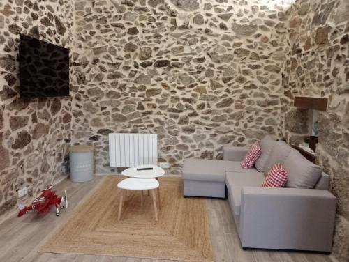 a living room with a couch and a stone wall at Apartamentos Muralla Sacra in Sober