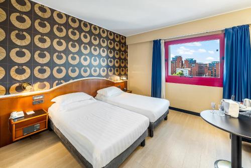 a hotel room with two beds and a table at Abacus Hotel in Sesto San Giovanni