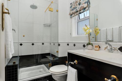 a white bathroom with a toilet and a sink at Neighbourgood Hill in Cape Town