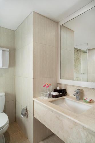 a bathroom with a sink and a toilet and a mirror at Atria Hotel Magelang in Magelang