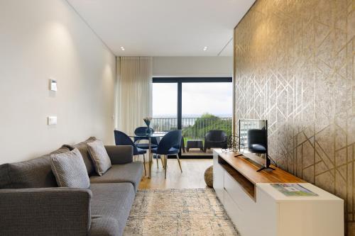 a living room with a couch and a tv at Dragão - Indigo Antas Park in Porto