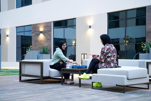 two women sitting on couches in front of a building at The Myriad Muscat - Female Only ذا ميرياد مسقط - للنساء فقط in Seeb
