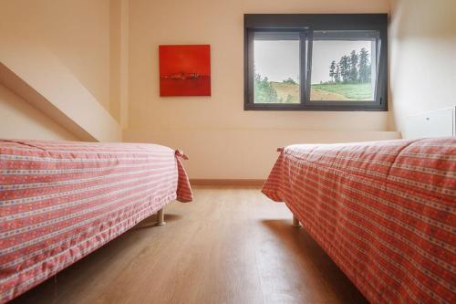 two beds in a room with a window at Beautiful townhouse 20km from Bilbao in Llodio