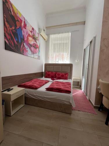 a bedroom with a large bed with red pillows at Sobe sa sopstvenim KUPATILOM Private rooms bathroom In CENTER in Novi Sad