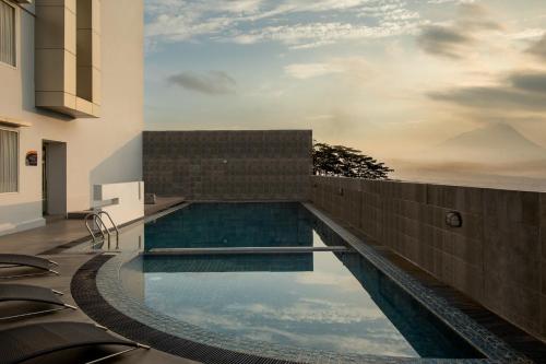 a swimming pool in a building with a reflection in the water at Atria Hotel Magelang in Magelang